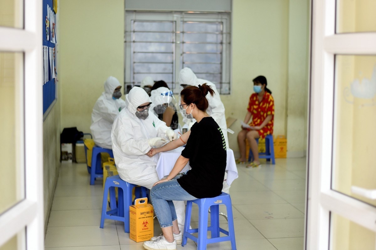 Health workers wearing protective suits collect blood samples at a makeshift rapid testing center in Hanoi on July 31, 2020.( Photo: AFP / Manan Vatsyayana)